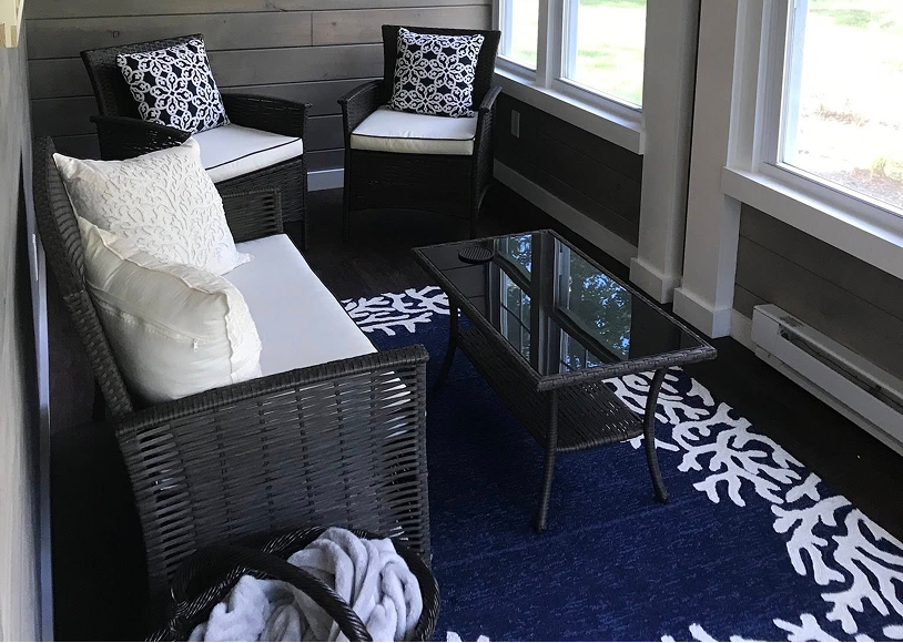 Cozy sunroom with wicker furniture and rug.