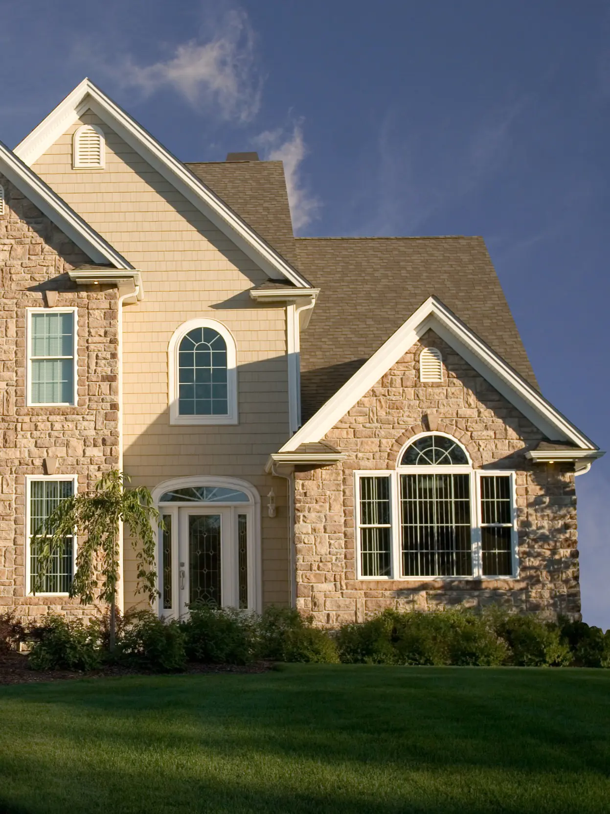 Stone and siding house under blue sky