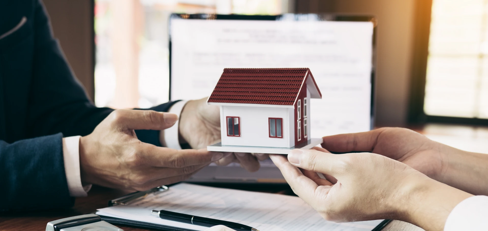 Hands holding small house in meeting